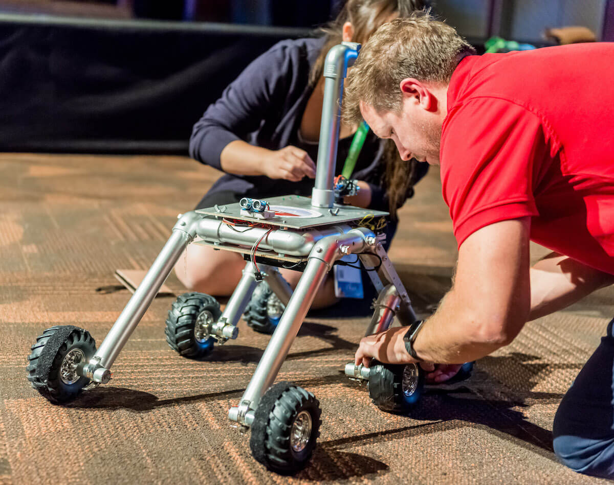 Attendees from tech groups get hands on experience with a Mars Rover at the welcome reception.